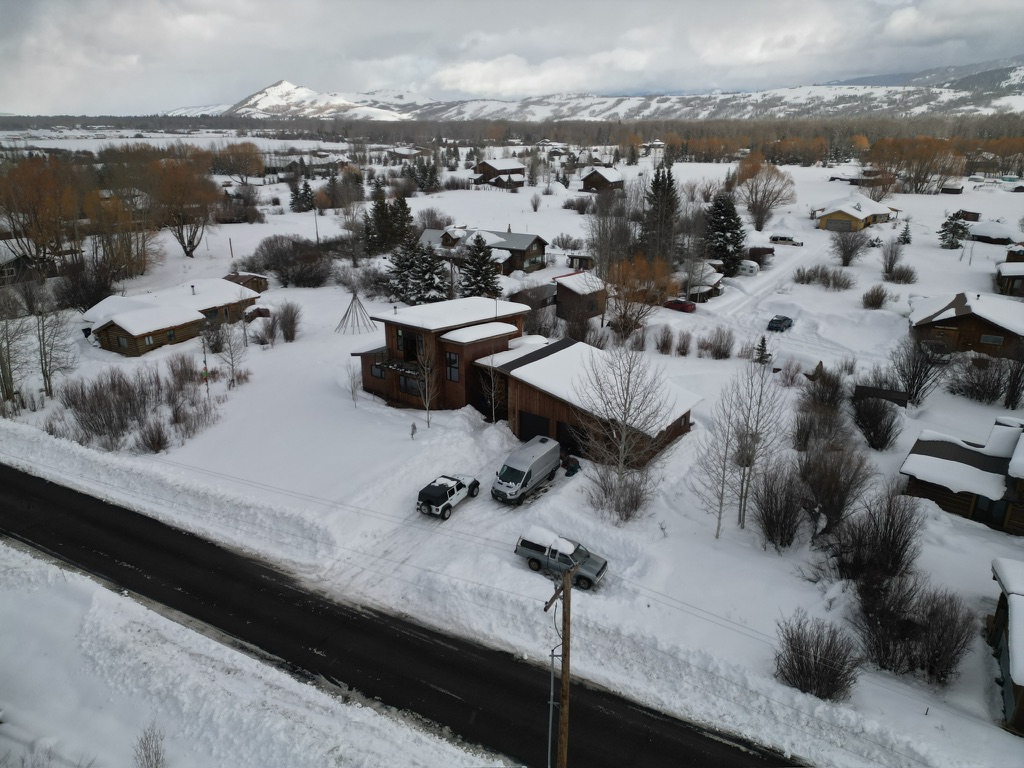 Aerial drone view of Jackson Hole home in winter with mountain backdrop